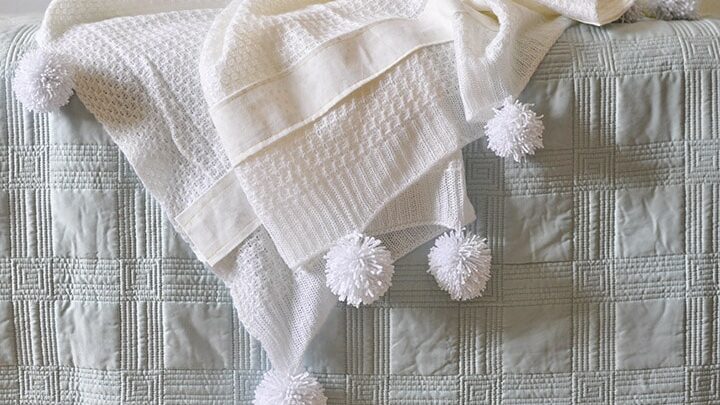 Learn to make a cozy Yarn Pom Pom Throw Blanket